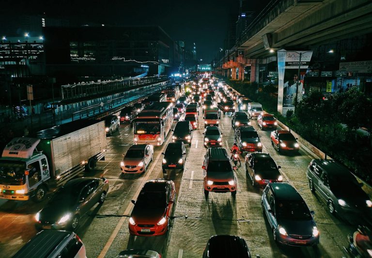 A bustling urban highway filled with cars and buses at night, showcasing city life and transportation.